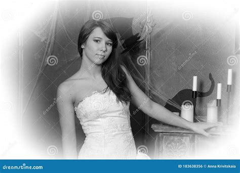 Beautiful Brunette Woman In A White Dress Indoors With Spider Web And Antiques Stock Photo