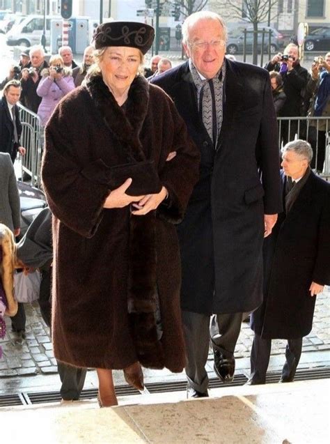 An Older Man And Woman Are Walking Down The Street In Fur Coats With