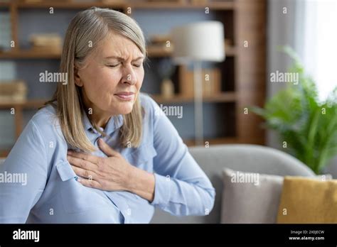 Mature Woman Experiencing Discomfort And Holding Her Chest Due To Pain She Seems Anxious And