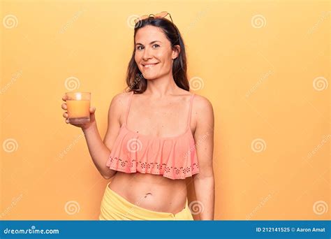 Beautiful Brunette Woman On Vacation Wearing Bikini Drinking Glass Of Healthy Orange Juice