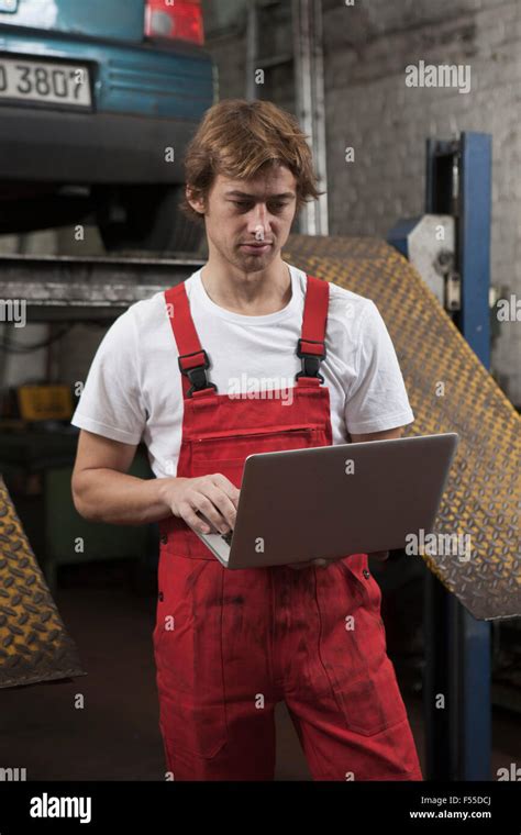 Mechanic using laptop at garage Stock Photo - Alamy