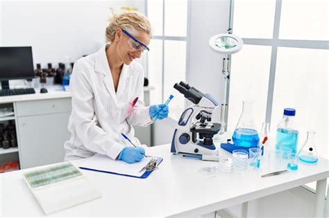 Middle Age Blonde Woman Wearing Scientist Uniform Holding Test Tube