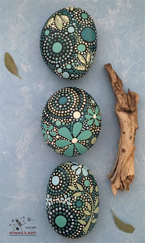 Three Painted Rocks Sitting On Top Of A Blue Surface