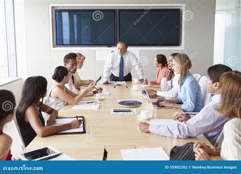 Group Of Businesspeople Meeting Around Boardroom Table Stock Photo