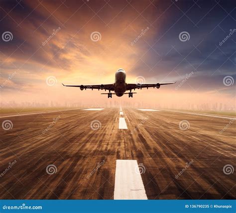 Air Plane Flying Over Airport Runway With City Scape And Sunset Sky