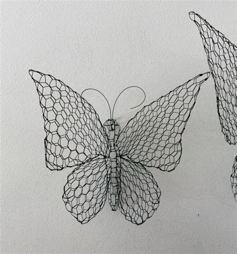 Two Wire Butterflies Hanging From The Side Of A Wall