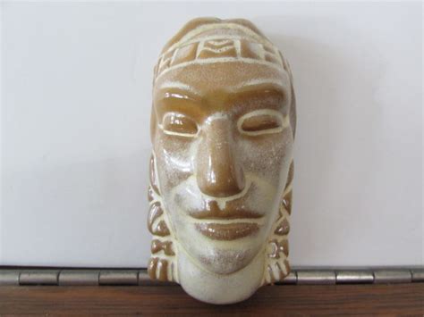 A Ceramic Mask Sitting On Top Of A Wooden Shelf