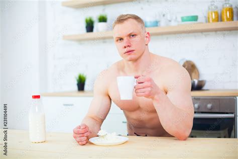 Muscular Man With A Naked Torso In The Kitchen With Milk And Cottage Cheese The Concept Of A