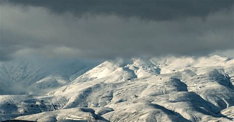 A snowy mountain range with a dark sky above · Free Stock Photo