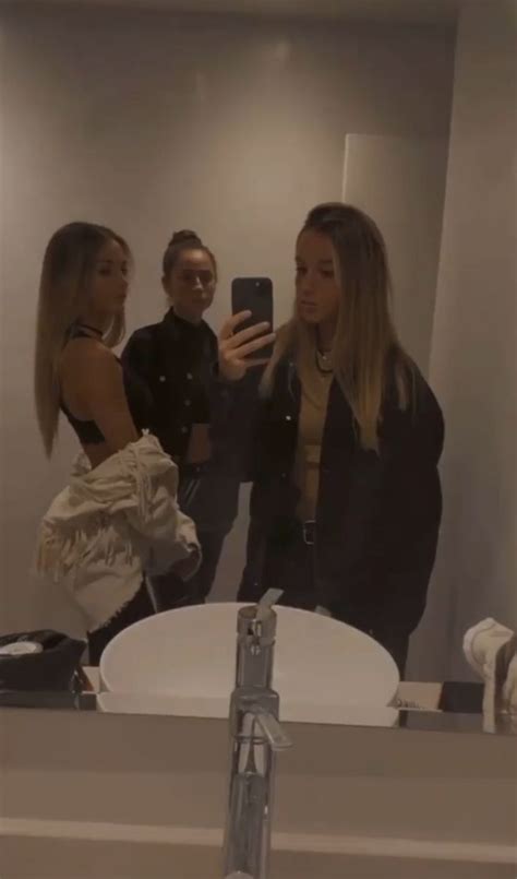 Two Women Are Standing In Front Of A Mirror Taking A Selfie With Their