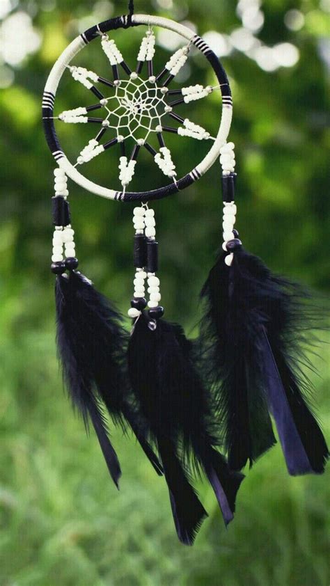 A Black And White Dream Catcher With Feathers Hanging From Its Side In