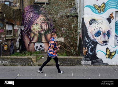 A Lady Walks Past Graffiti And Urban Artwork That Features Pandas And A