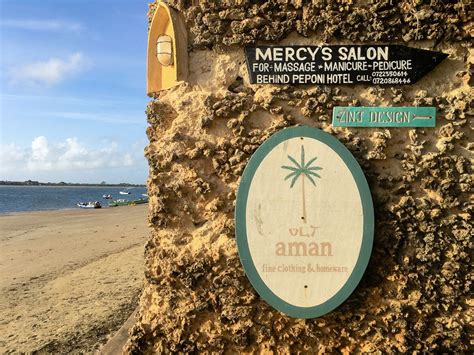 A Sign On The Side Of A Stone Wall Next To The Ocean With Boats In The