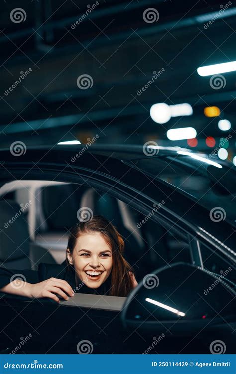 Vertical Photo From The Side At Night Of A Woman Sitting In A Car And