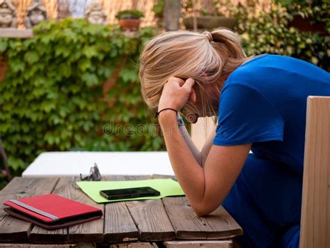 Adult Depressed Blonde Woman Hunched Over On Her Hands Sitting In The Garden Stock Photo Image