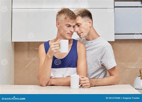 Beautiful Cute Gay Couple Drinking Coffee In The Morning In The Bright Kitchen Stock Photo