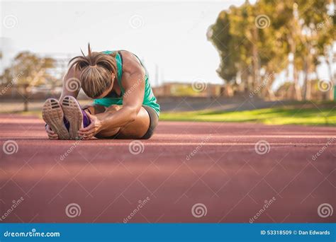 Atleta De Sexo Femenino Que Estira En Una Pista Corriente Imagen De