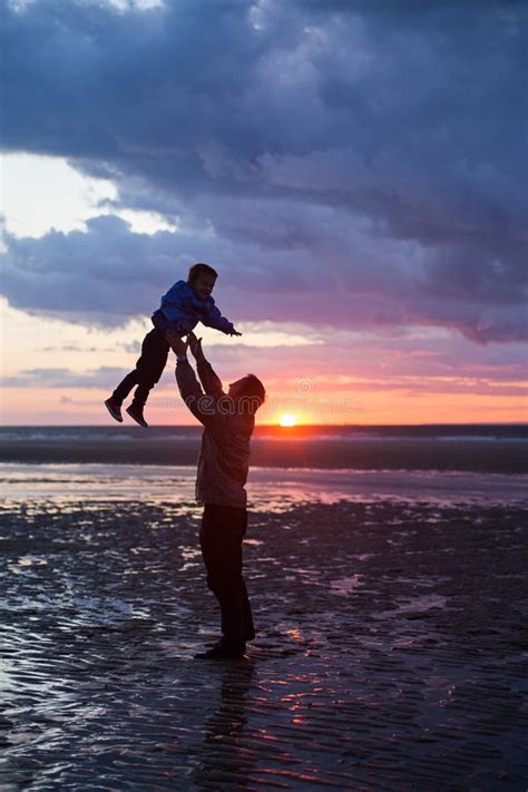 Father And Son Play On The Beach In Sunset Silhouette Shot Stock Image