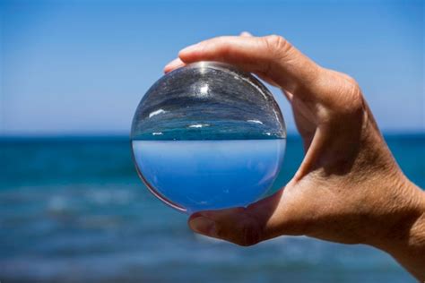 Premium Photo Cropped Hand Of Person Holding Crystal Ball Against Sea