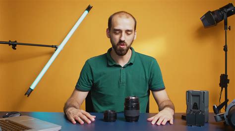 Photographer holding lenses to camera while recording online workshop