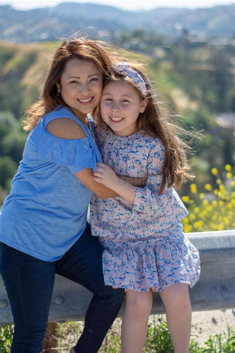 Madre E Hija De Latina Que Sonr En Y Que R En En Una Colina Delante De Las Flores Amarillas Foto