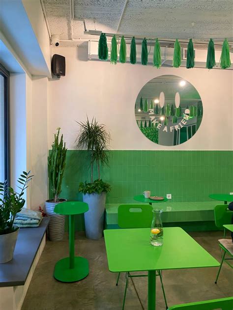 Green Tables And Chairs In A Room With Mirrors On The Wall Above Them