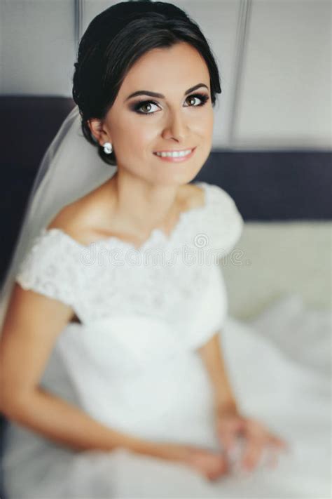 Brunette Bride Smiles Sitting On The White Bed Stock Photo Image Of Dress Light