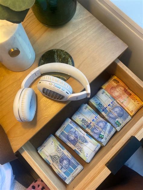 A Wooden Table Topped With Lots Of Money And Headphones