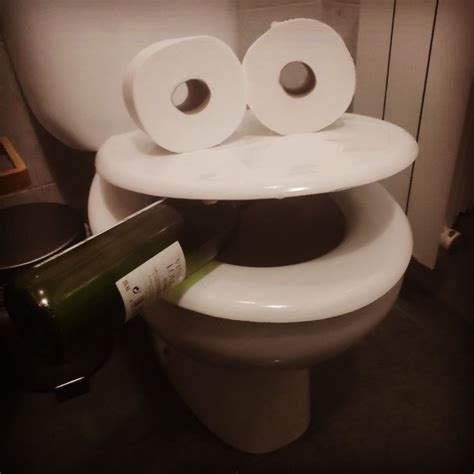 Two Rolls Of Toilet Paper Stacked On Top Of Each Other Next To A Wine