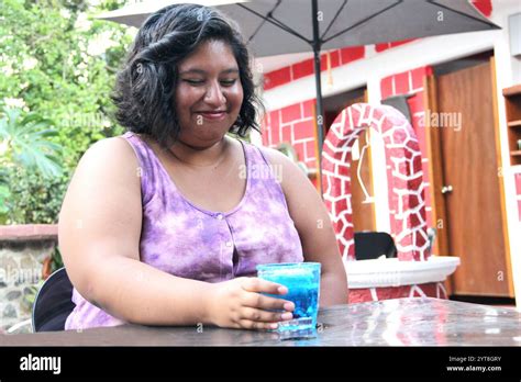 20 jährige Brünette Latina trinkt einen Azulito Cocktail oder ein alkoholisches Getränk mit