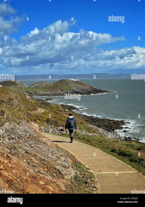 Walker on the Wales coastal path, heading towards Limeslade Bay from Langland Bay, April Stock ...