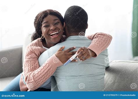 Emotional Black Woman With Pregnancy Test Hugging Her Husband Stock