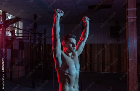 Muscular Powerful Man With Naked Torso Trains With Expander Fitness Rubber Bands In Red Blue