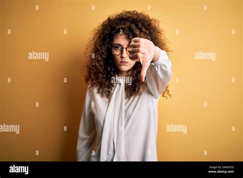 Jeune belle femme brunette avec des cheveux bouclés et piercing portant une chemise et des