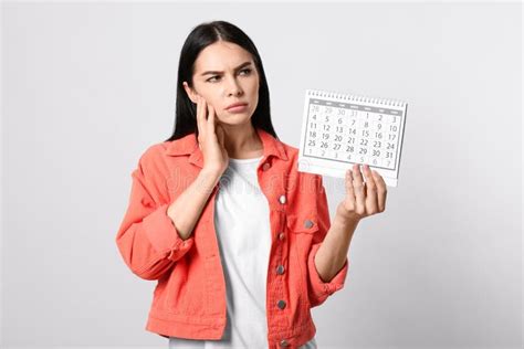 Pensive Young Woman Holding Calendar With Marked Menstrual Cycle Days