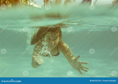 The Little Girl In The Hotel Pool Swimming Underwater And Smiling Stock