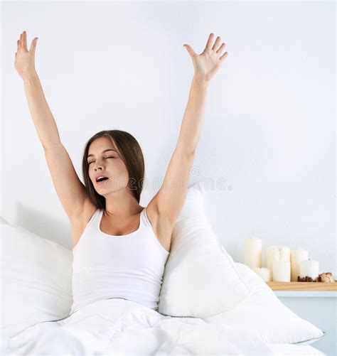 An Attractive Young Woman Stretching In Bed After Waking Up Stock