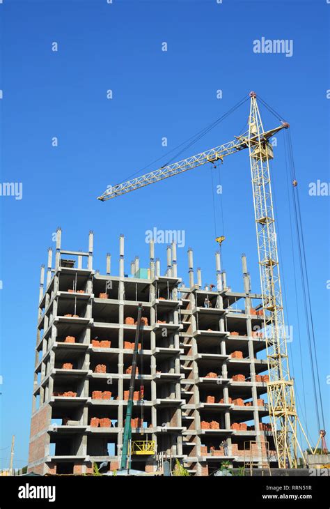 Building Cranes On Construction Site With Builders Building High Rise