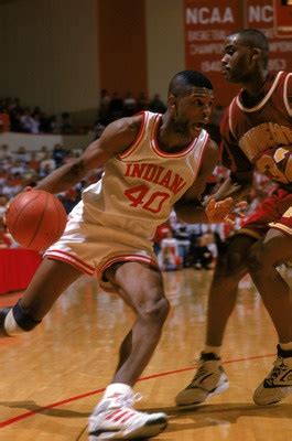 Two Men Playing Basketball On A Court With People Watching From The