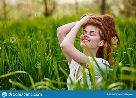 Portrait Of A Beautiful Woman Sitting In Tall Grass And Holding Her