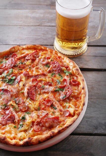 Premium Photo Tasty Pizza And Glass Of Beer Are On Wooden Table Close Up