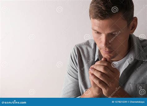 Man With Hands Clasped Together For Prayer On Light Background Stock