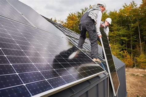 Workers Lifting Up Photovoltaic Solar Module While Installing Solar