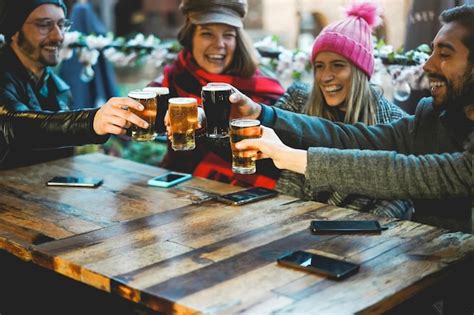 Premium Photo Young People Having Fun Cheering With Beer At Pub