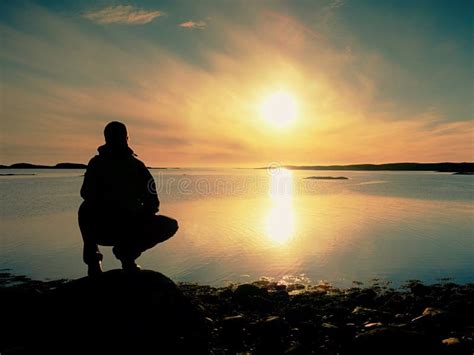 Hiker In Squatting Position On A Rock Enjoy Dybreak Scenery Stock