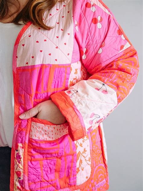 A Woman Wearing A Pink And Orange Quilted Jacket With Her Hands In Her