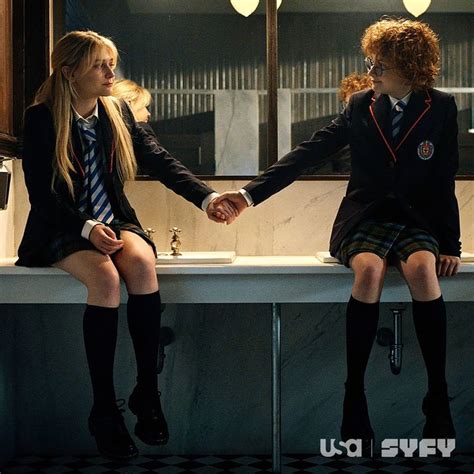 two girls in school uniforms are sitting on a counter and one girl is ...