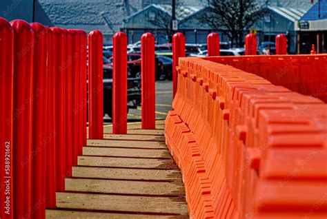 Orange heavy-duty plastic barriers are set up on the sidewalk while ...