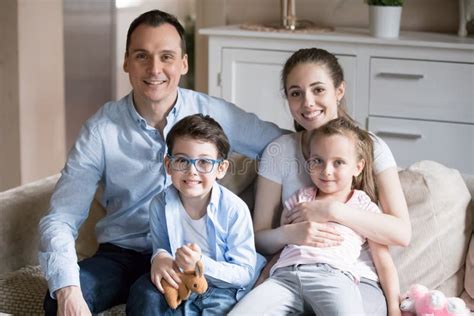 Retrato De La Familia De Cuatro Miembros Joven Feliz Que Presenta Para