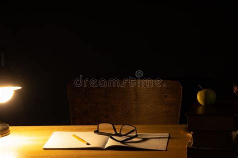 Table Lamp Desk Notebook And Books Next To Chair In Dark Room